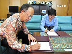 贈与契約書に署名する鹿取大使（左）と梶田未央統括（右）